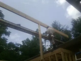Carpenter setting a ridge beam over a new addition frame — Ice Dam Removal by Roofing Brothers in Oskaloosa