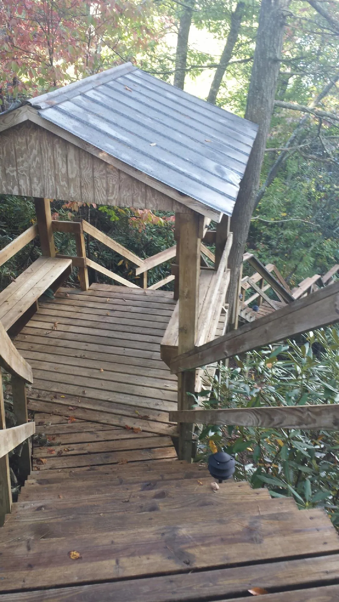 Metal roofed shelter over wooden steps on a wooded walkway — Skylight Repair & Installation work by our crew in Oskaloosa