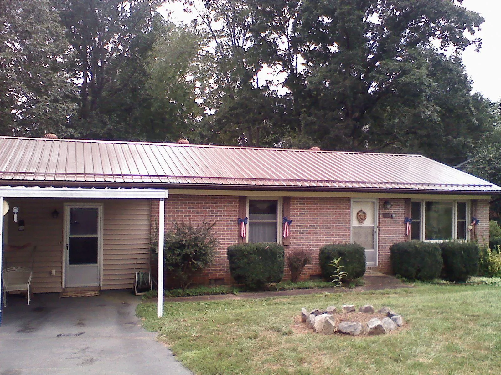 Bronze metal roof and carport on a brick ranch home — Roof Repair work by our crew in Oskaloosa