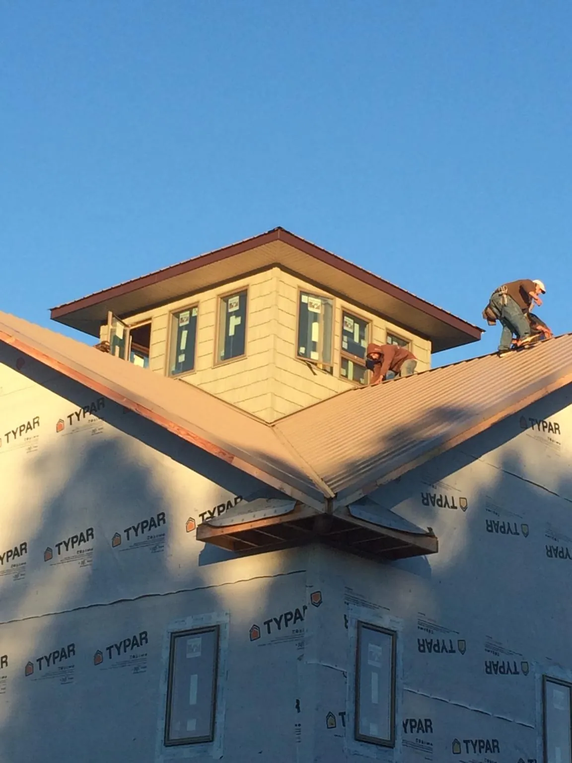 Roofers working around a rooftop cupola on a new metal roof at sunset — Roof Waterproofing in Oskaloosa by Roofing Brothers